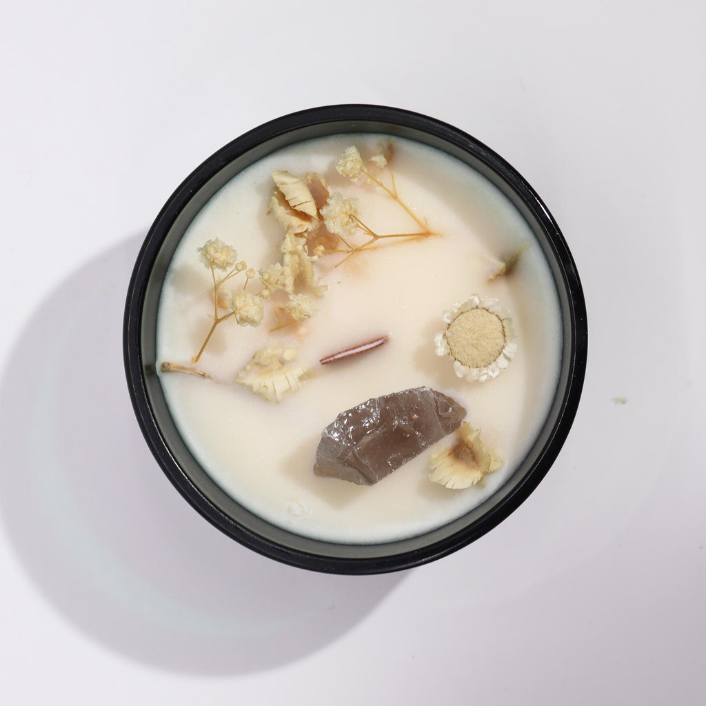 Viewed from above; a green glass candle with Rock Quartz gemstones embedded in and some dried flowers. 