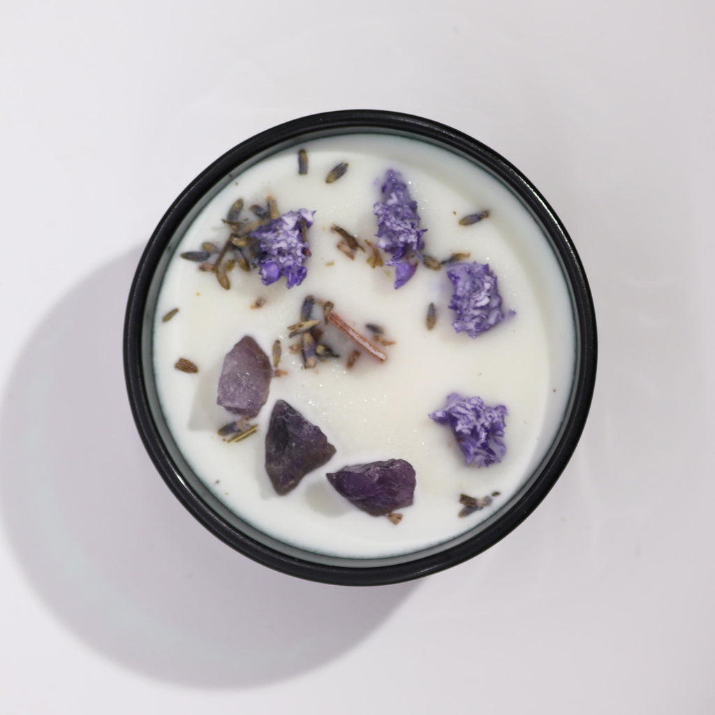 Viewed from above: A green glass candle with lavender flowers and Amethyst gemstones inside.