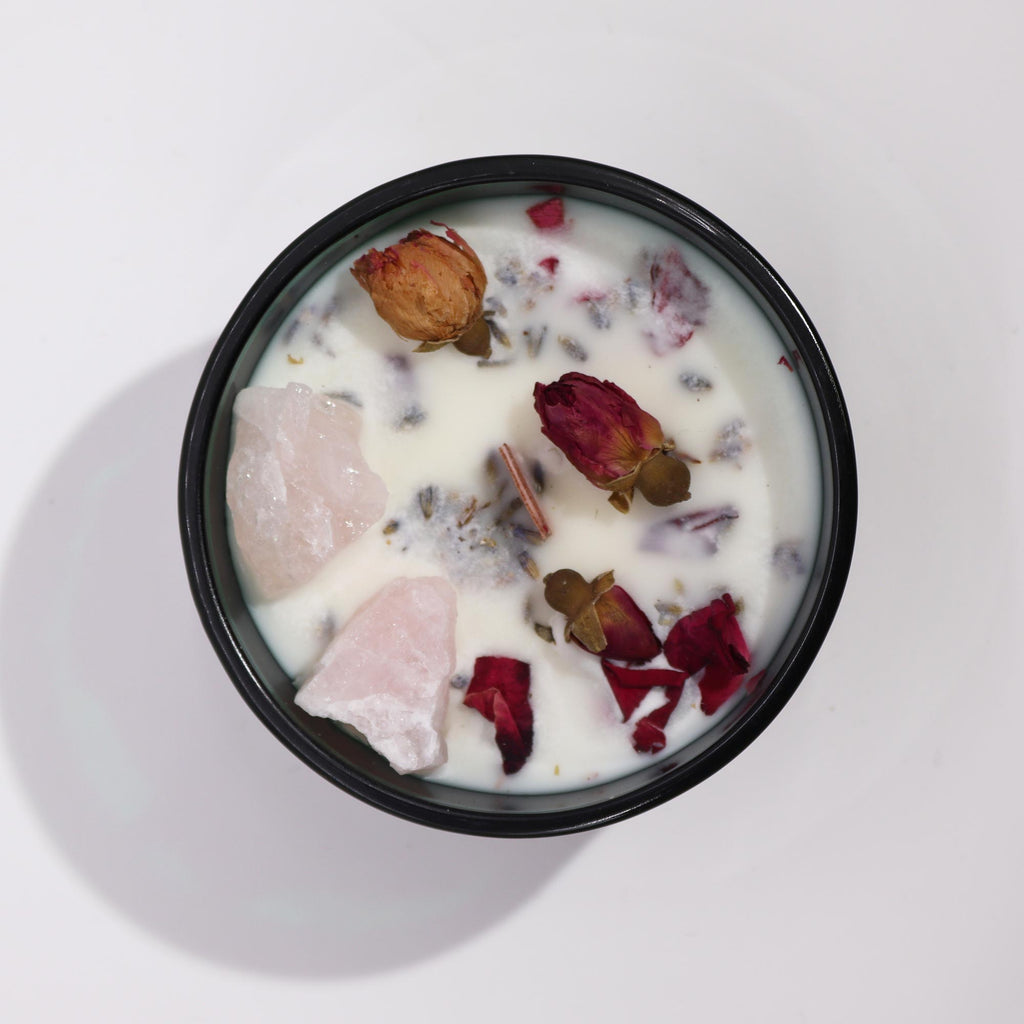 Viewed from above: a green glass crystal magic flower candle, adorned with dry flowers and rose quartz gemstones.