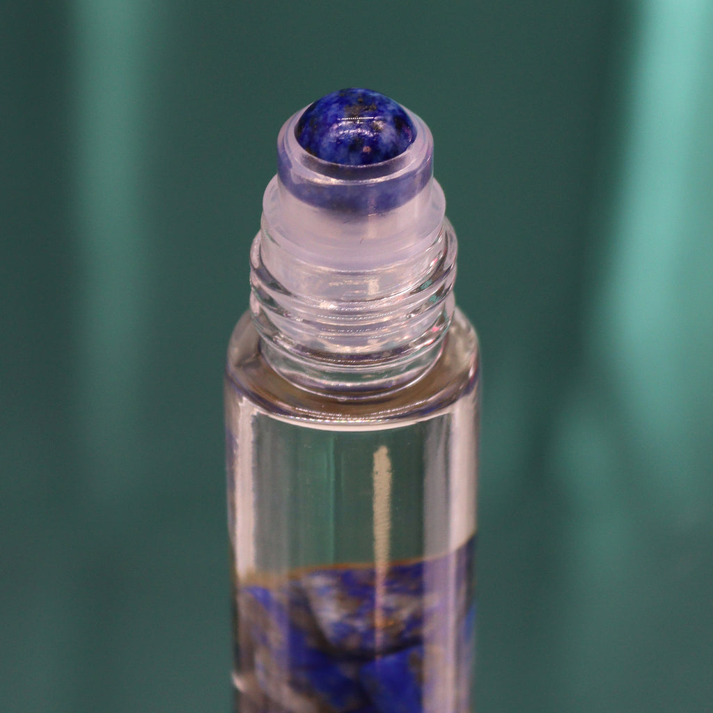 A close up of an essential oil roll on glass bottle with blue gemstones