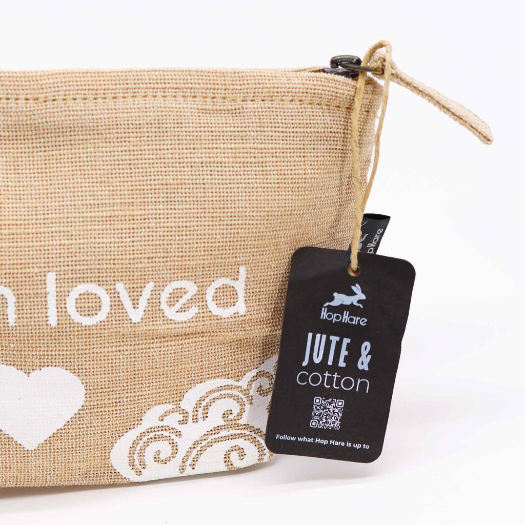 A beige jute pouch with an 'I am loved' affirmation in white. 