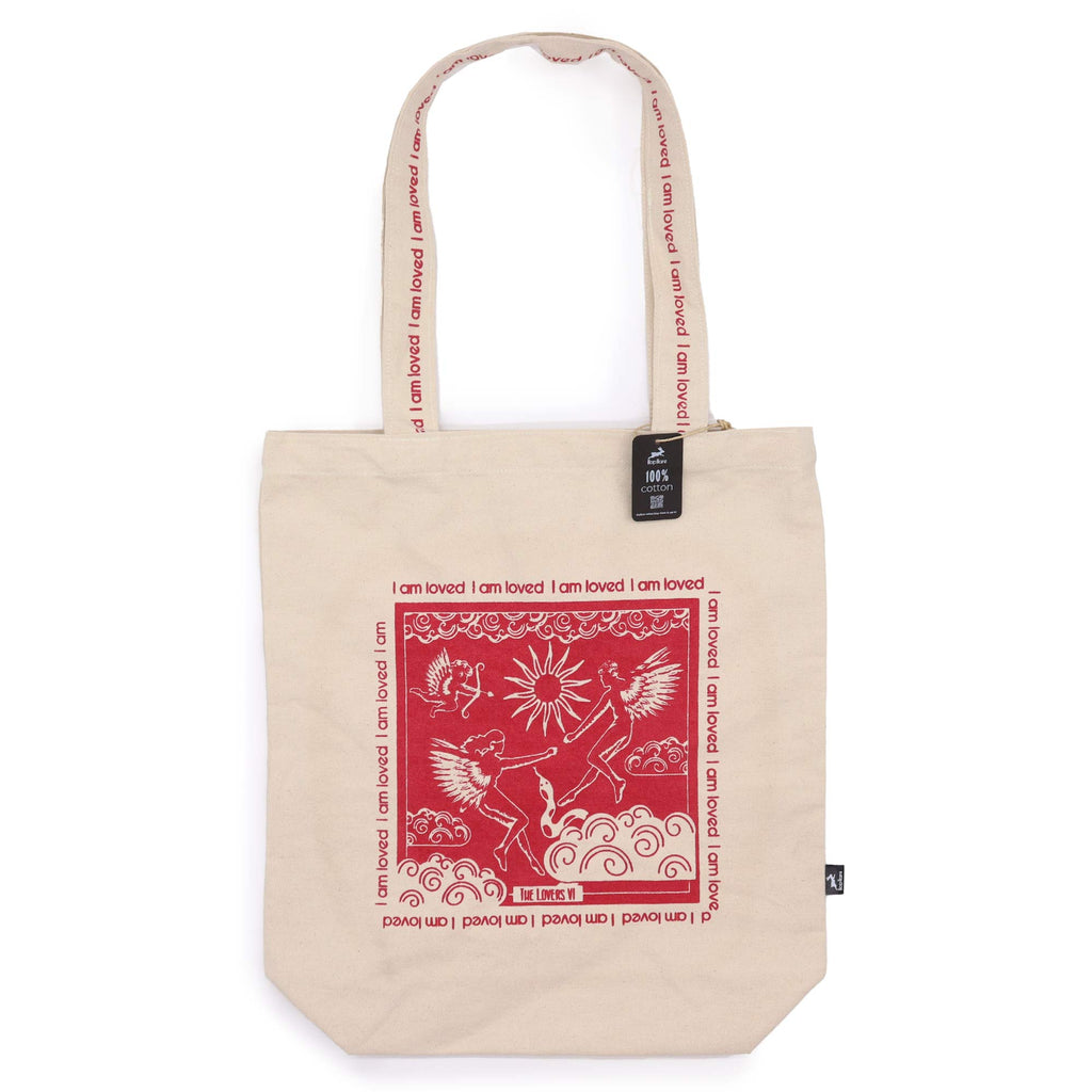 Tote bag with pink motif which is of a "the lovers" holding hands out to each other while flying, with an affirmation "I am loved" repeated around the motif. 