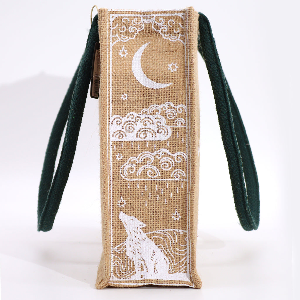 A beige jute bag, with green handles, with the text 'I am powerful' printed on the side, featuring a moon and wolf design.