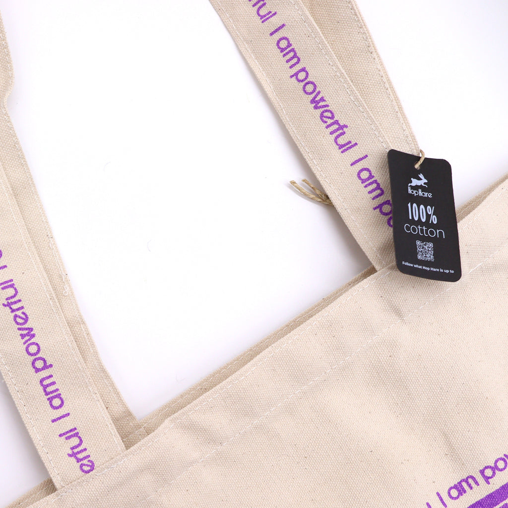 Tote bag with purple motif which is of wolves howling to the moon with the affirmation "I am powerful" repeated around the motif. 