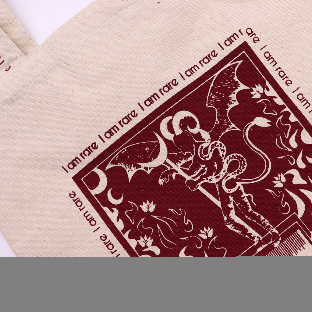 Tote bag with red motif which is of a "devil" with the affirmation "I am rare" repeated around the motif. 
