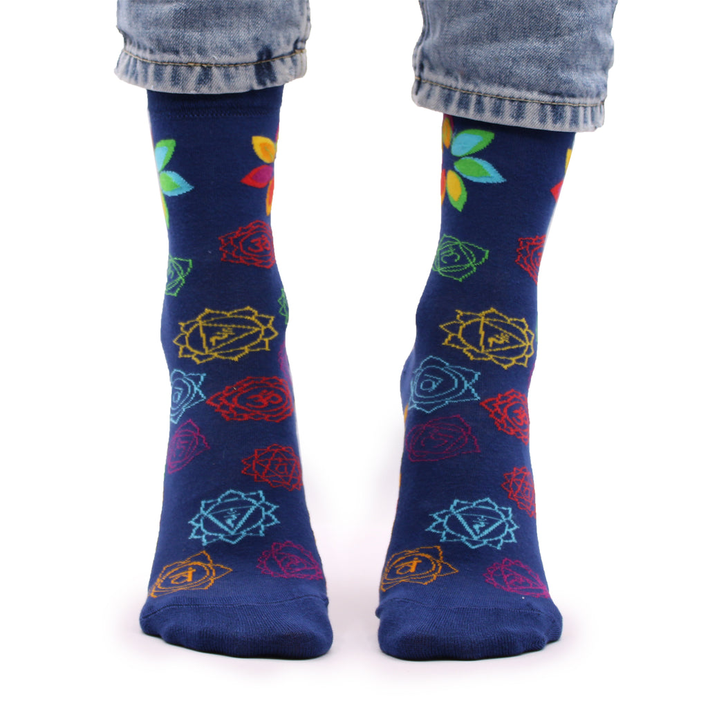 A pair of navy blue socks with colourful chakra patterns, worn on someone's feet