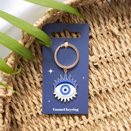 A blue and white all-seeing eye key ring on a cardboard backing with a woven background.