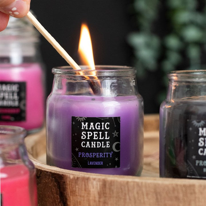 A small lit purple Magic Spell Candles with a label that states it is for "Prosperity" and is Lavender 