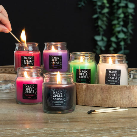 A collection of small magic spell candles in various colours or various purposes such as protection and friendship, all are lit. 