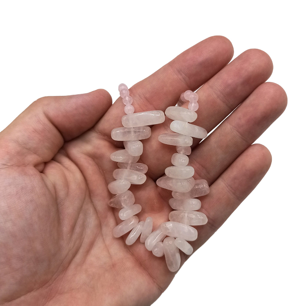 A pink longstone Rose Quartz necklace held in a hand.