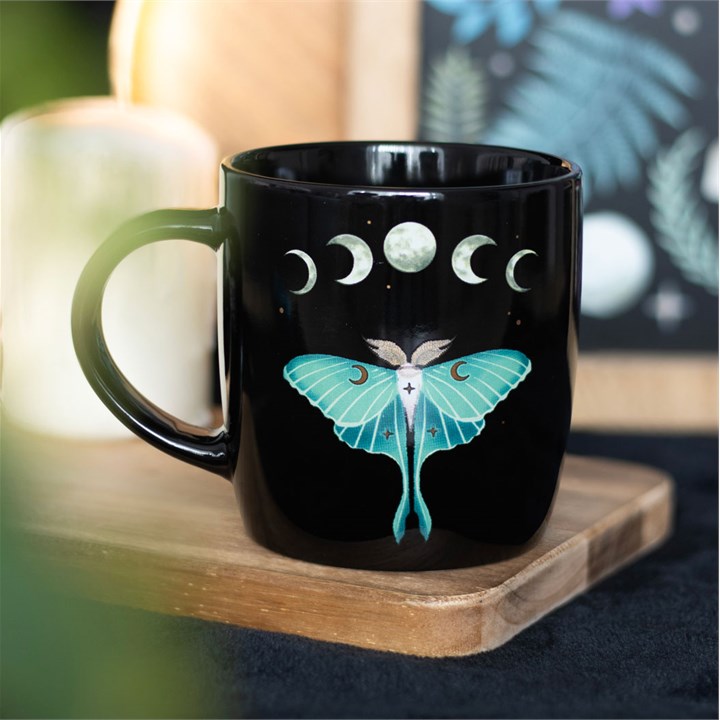 A dark forest lunar moth mug displayed on a wooden tray.
