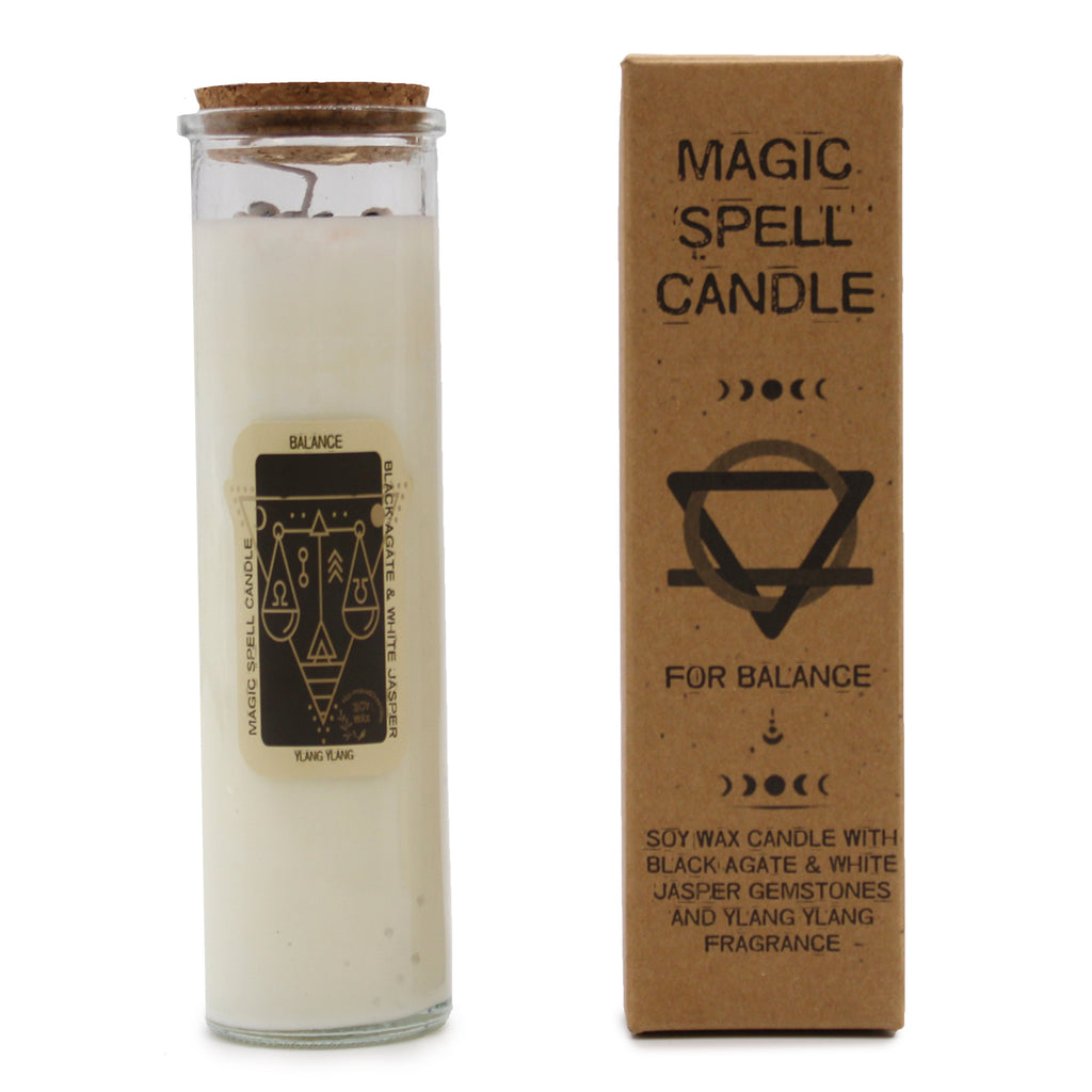 A "Balance" Magic Spell Candle with embedded gemstones. The candles are made of soy wax and have glass containers with cork stoppers. It is next to its brown packaging.