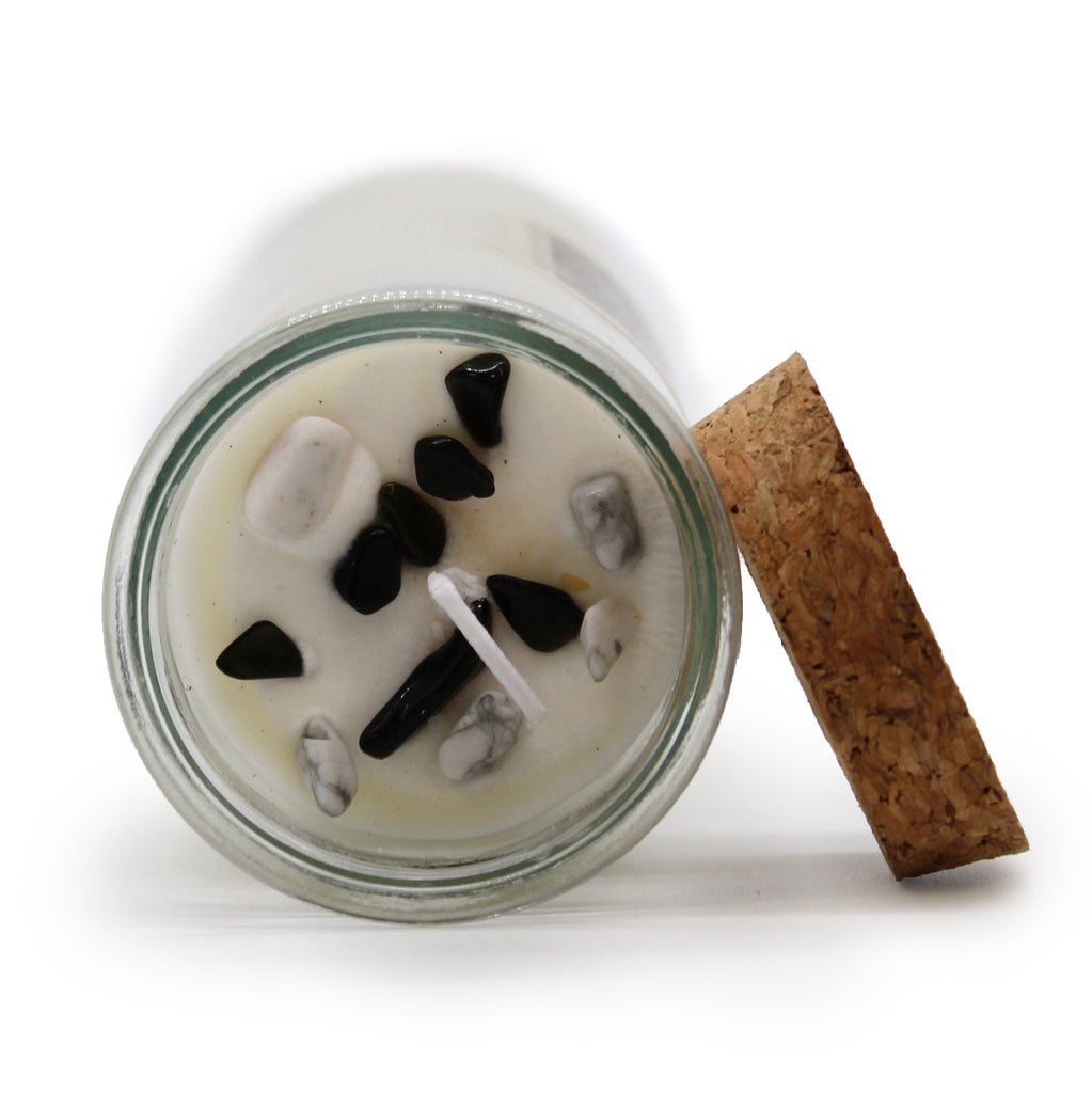 A top view of a Magic Spell Candle with embedded gemstones laid next to its cork stopper.