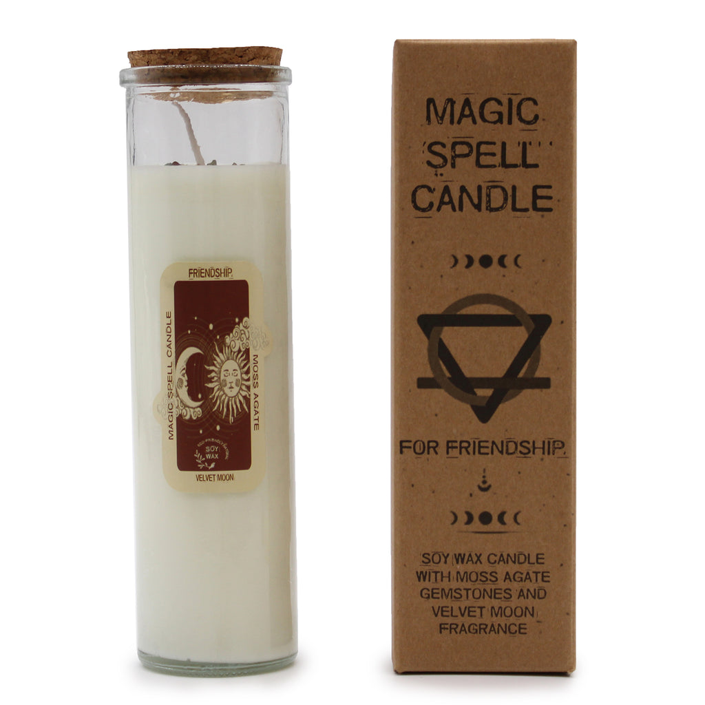 A "Friendship" Magic Spell Candle with embedded gemstones. The candles are made of soy wax and have glass containers with cork stoppers. It is next to its brown packaging.
