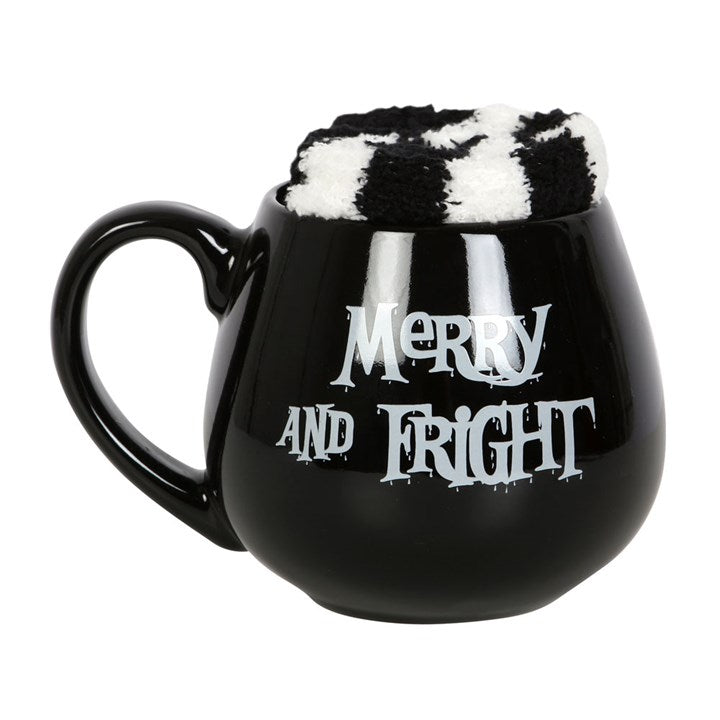 A black ceramic mug with 'Merry and Fright' text with a pair of black and white striped socks inside it.