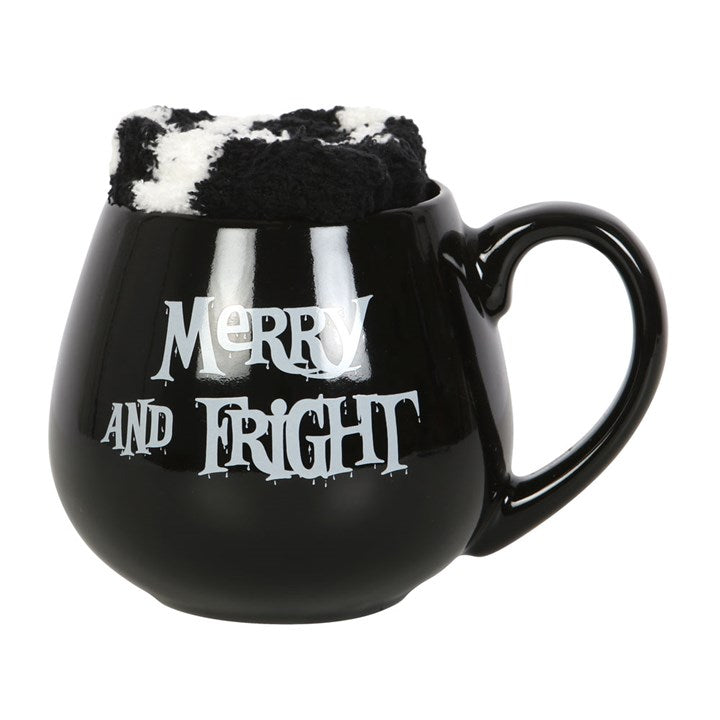 A black ceramic mug with 'Merry and Fright' text with a pair of black and white striped socks inside it.