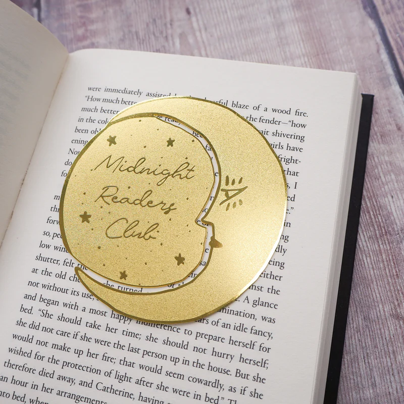 Brass 'Midnight Readers Club' bookmark on an open book