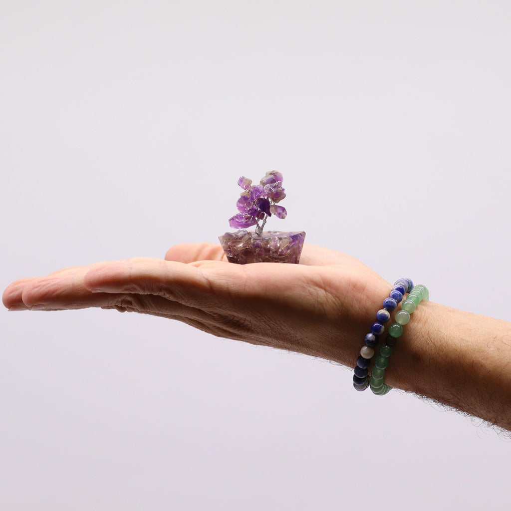 A mini amethyst tree on an orgonite base held in an open hand