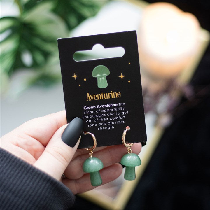 Mushroom shaped green aventurine earrings on a black card being held in a hand