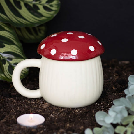 A white ceramic mug with a red mushroom-shaped lid and dots pattern on the lid.