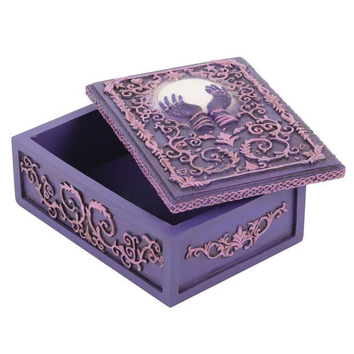 A pink and purple resin storage box with a mystical hand and crystal ball design, featuring raised filigree details, with the lid ajar
