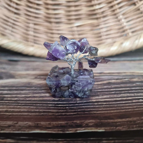 A mini Amethyst tree on an orgonite base, displayed on a wooden surface 