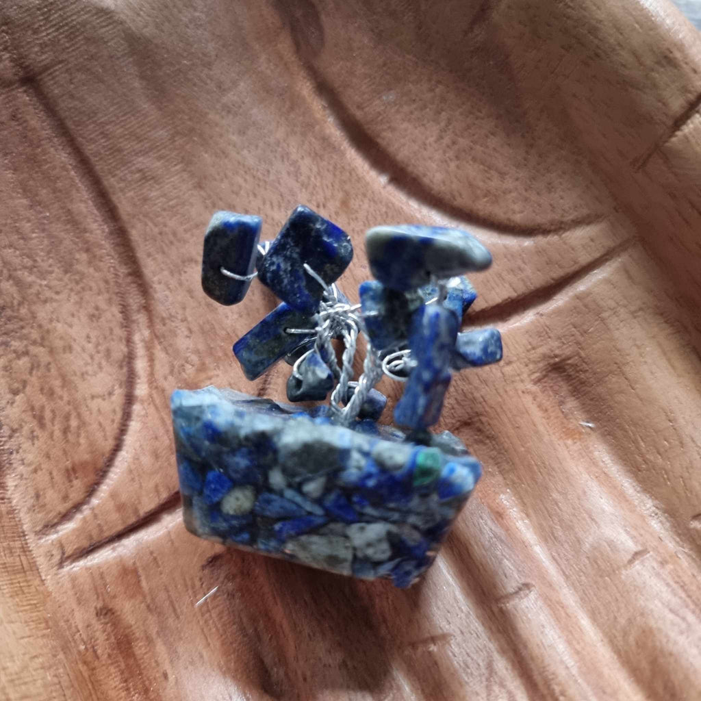 A mini sodalite tree on an orgonite base, displayed on a pair of wooden hands