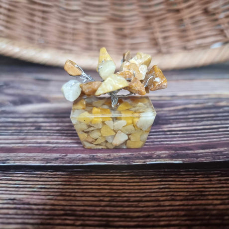 A mini yellow jasper tree on an orgonite base, displayed against a woven background.