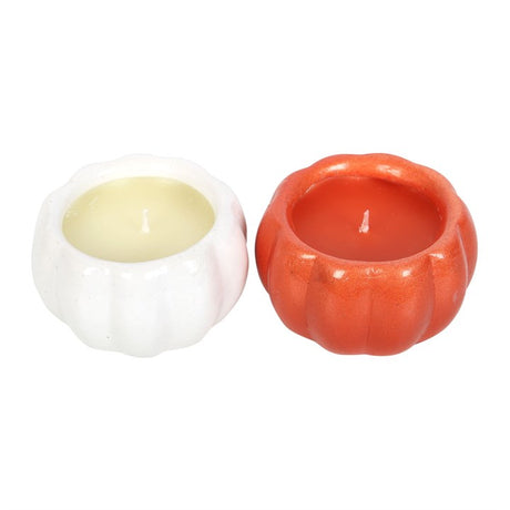 Two pumpkin-shaped candles, one in white and one in orange colour, with visible wicks