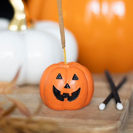 A small, smiley pumpkin incense holder