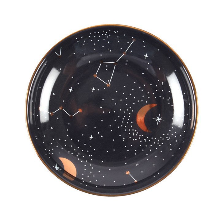A ceramic trinket dish with a dark blue background featuring celestial patterns, including stars and constellations