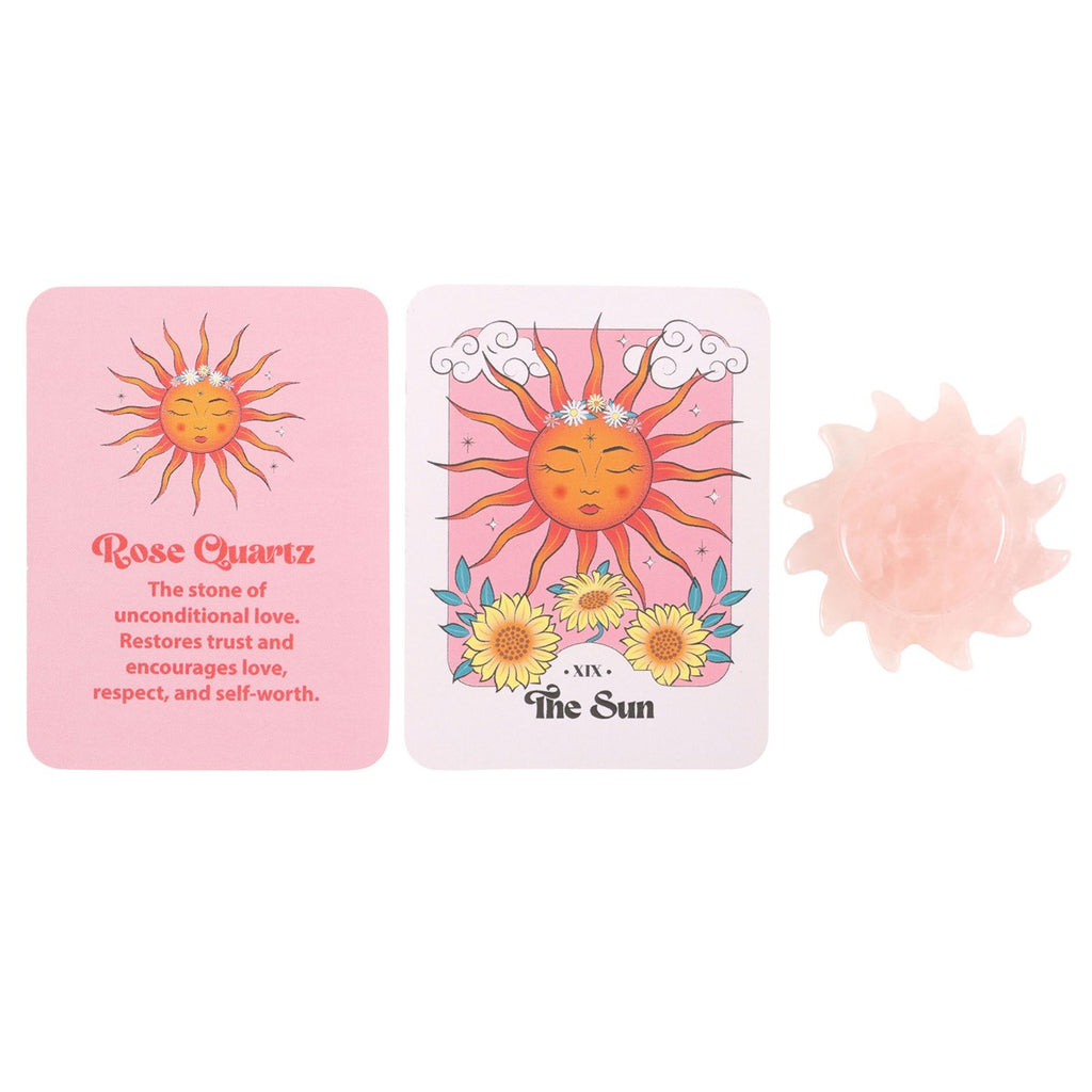 A carved Rose Quartz crystal sun alongside its packaging, which includes a card with the text 'Rose Quartz' and 'The Sun' indicating a tarot card-inspired design. 