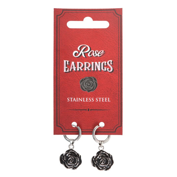 A pair of silver stainless steel rose earrings dangling from a card with a red background