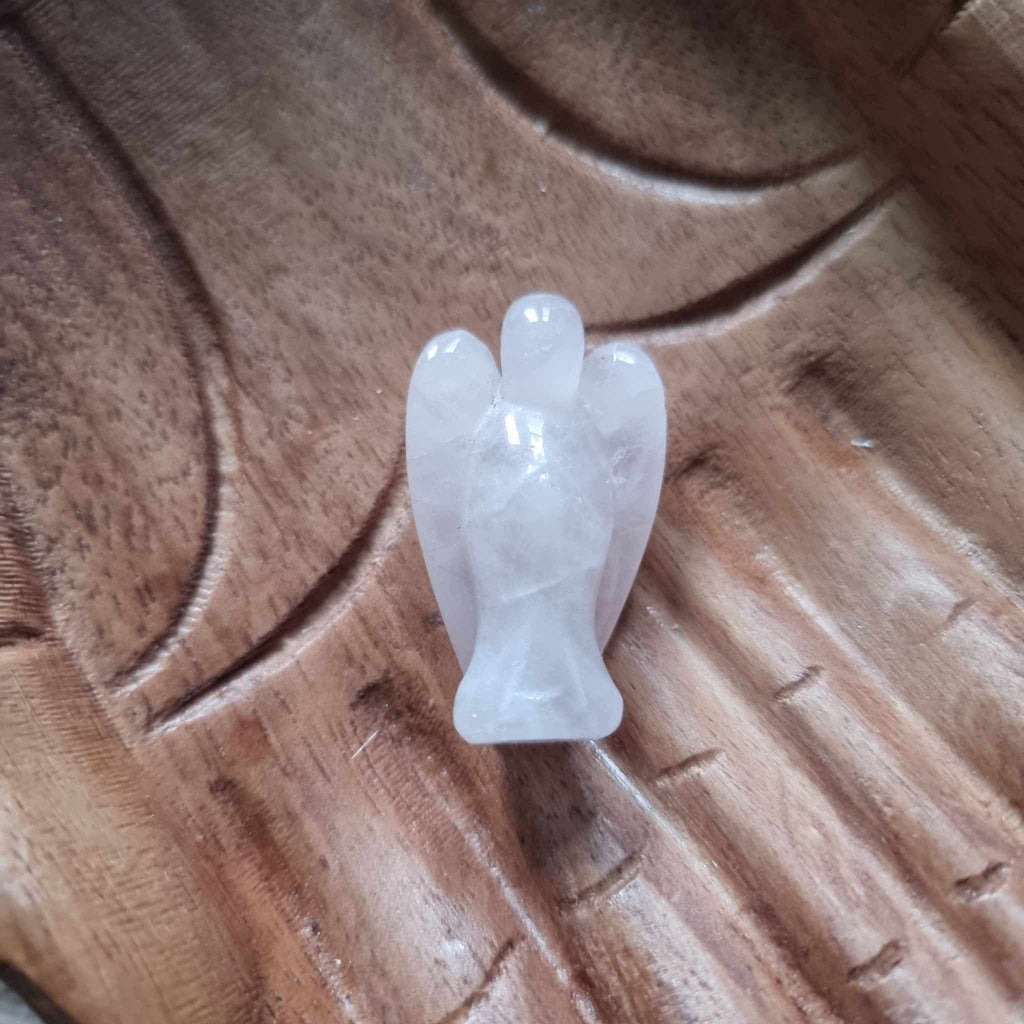 A pink crystal angel on a wooden backdrop 