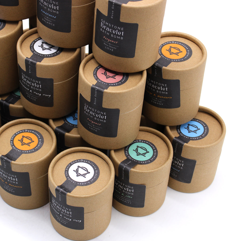 Several brown packages with black labels holding bath bombs and crystal bracelets. 