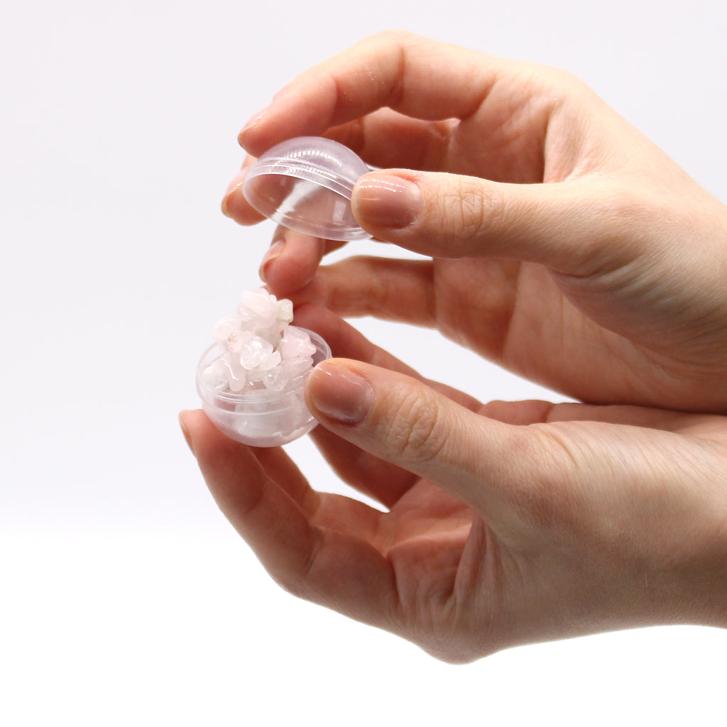 A clear capsule holding a rose quartz chipstone bracelet being opened by someone. 