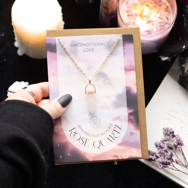 A hand holding a Rose Quartz Necklace card and envelope set