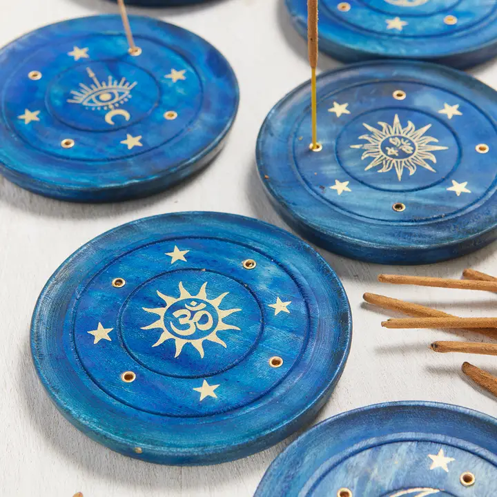 Blue incense holders with celestial designs on a white surface