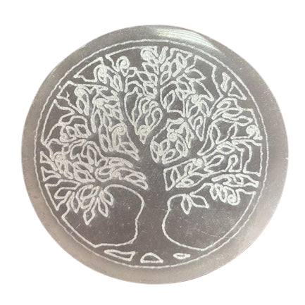 A round selenite crystal charging plate with an engraved Tree of Life design, against a white background. 