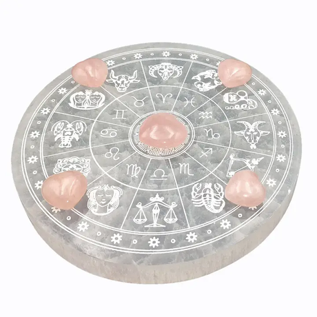 Round selenite charging plate with zodiac symbols and pink stones on a white background