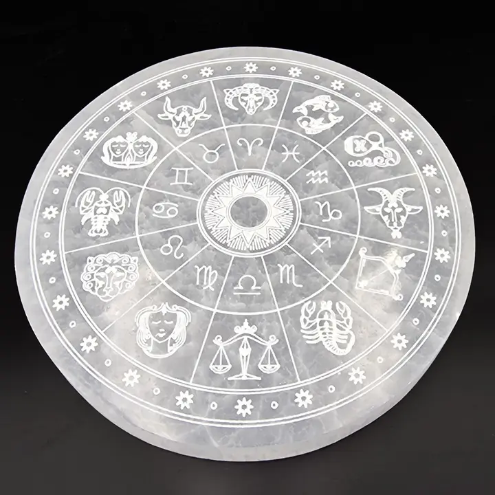 Circular selenite plate with zodiac symbols on a black background