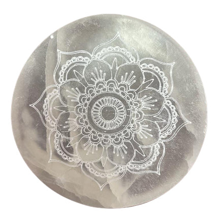 A round selenite charging plate with a mandala pattern etched into it, placed on a white background