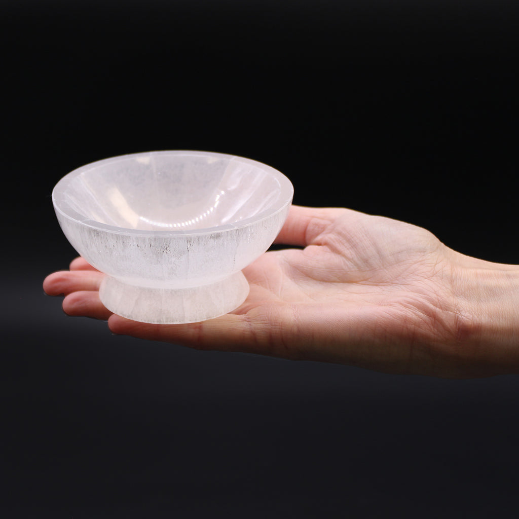 Selenite bowl held in a hand against a black background