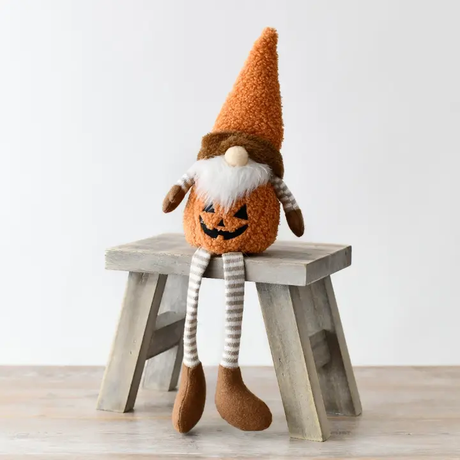 Halloween-themed gonk with pumpkin face on a wooden stool against a white background