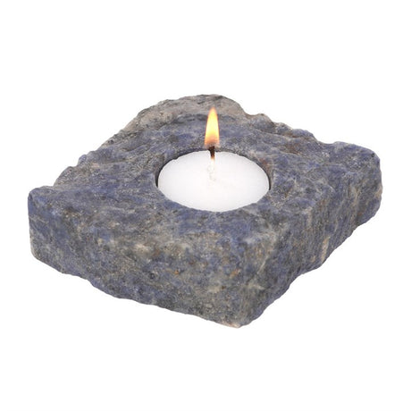 A rough blue sodalite tealight holder with lit candle