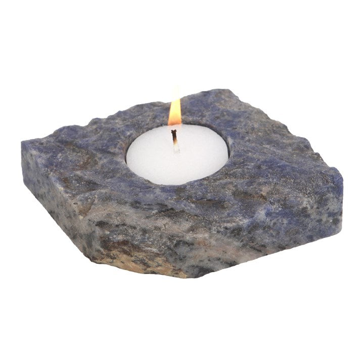 A rough blue sodalite tealight holder with lit candle