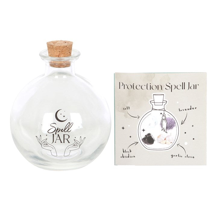 An empty, clear glass spell jar, closed with a cork stopper and a spell book.