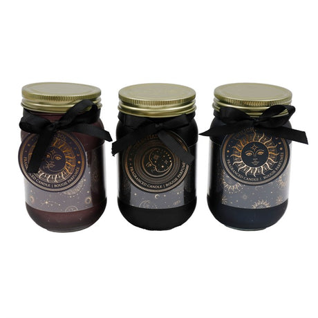 Three jar candles with celestial designs, in colours black, purple, and blue, each with a metal lid and a black ribbon around it.
