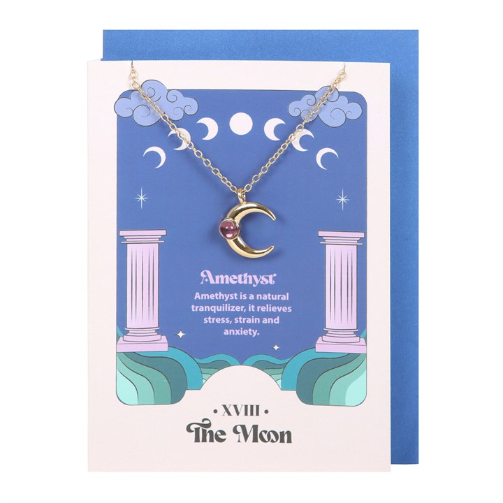 A stainless steel necklace with a crescent moon pendant and an amethyst crystal, displayed on a blue greeting card with tarot card designs and a blue envelope against a white background 