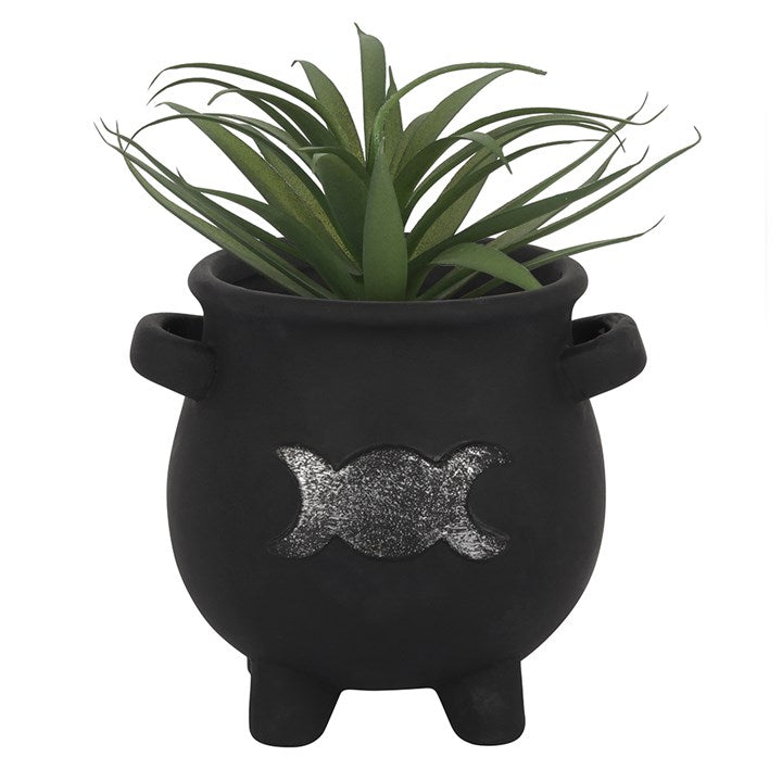 A black terracotta cauldron plant pot with a silver triple moon design, containing green artificial plants against a white background